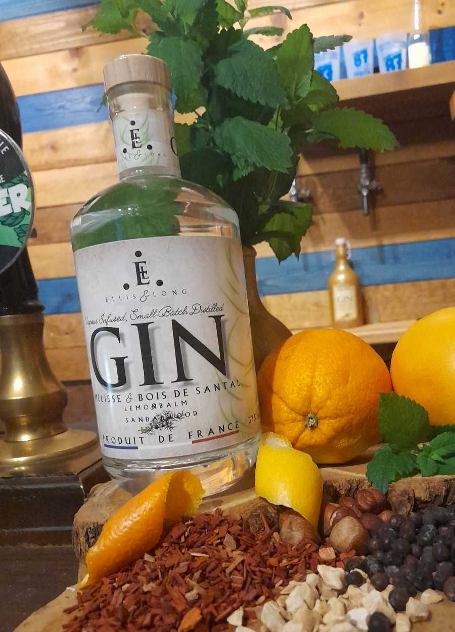 A bottle of Lemon Balm & Sandalwood Gin surrounded by botanicals on the bar at the distillery.